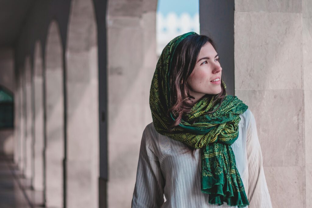 A woman in a green headscarf stands in a light-filled passageway in Kasur, Pakistan.